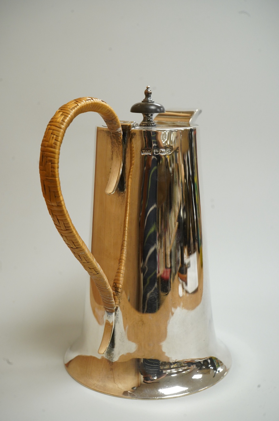 A George V silver hot water jug, by Walker & Hall, Sheffield, 1922, of tapering form, with rattan handle and circular spreading foot, height 22cm, 24.7oz.
